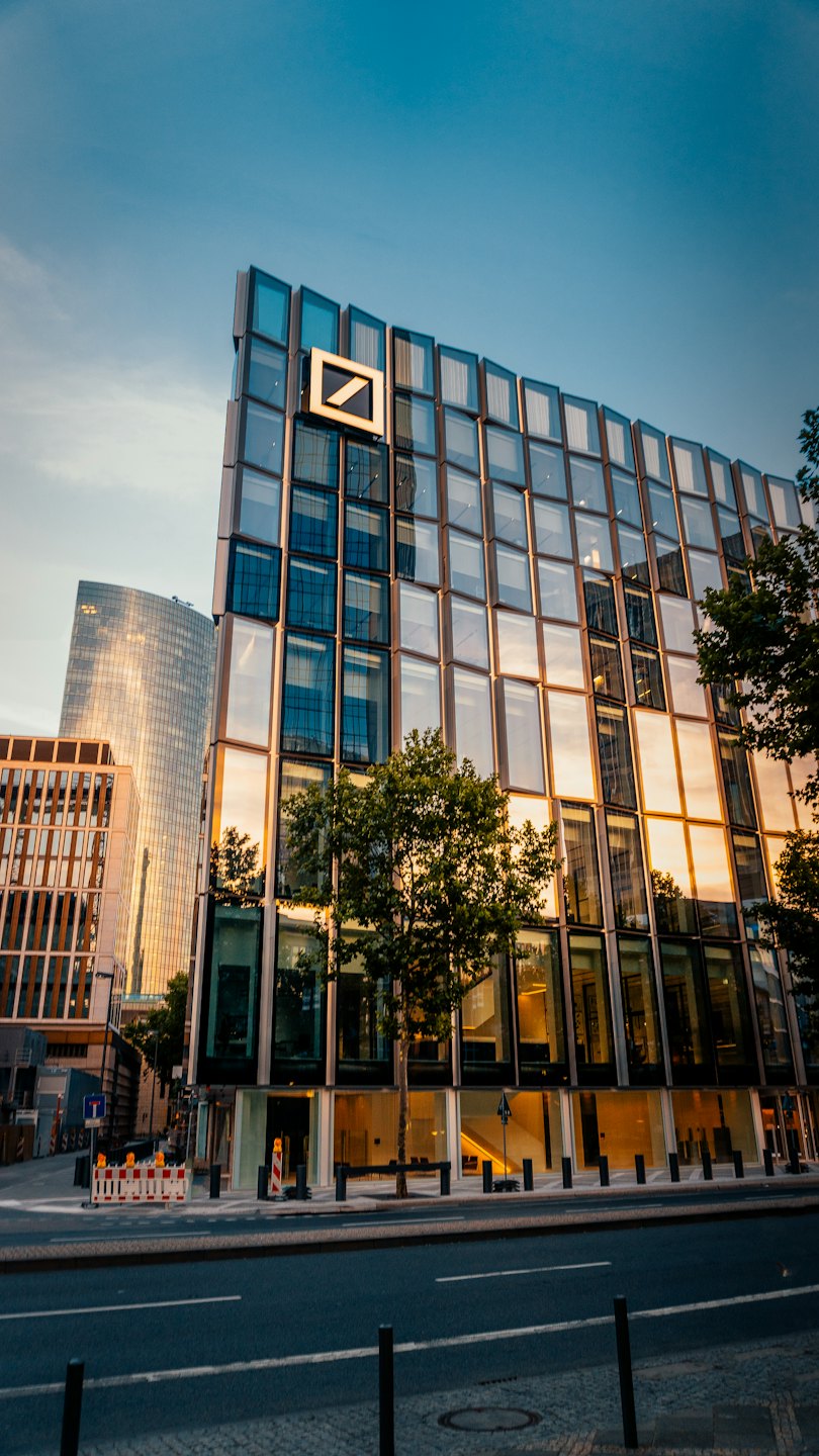 Moderná kancelárska budova s logom firmy odráža západ slnka.