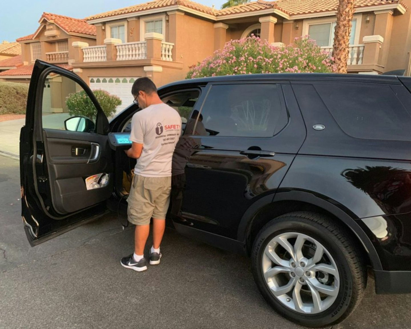 Zámočník programuje kľúč od auta na paneli dverí SUV za súmraku.