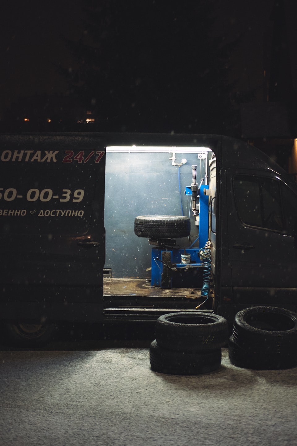 Mobilná pneuservisná dodávka otvorená v noci s osvetleným vybavením.